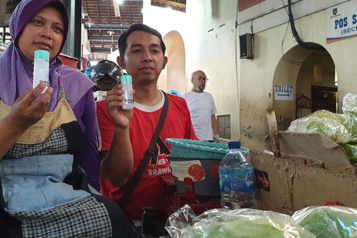Pedagang sayur dan buah, Yatmi, dan rekannya menunjukkan hand sanitizer yang diberikan secara gratis untuk komunitas pasar tradisional di Solo, 21 Maret 2020