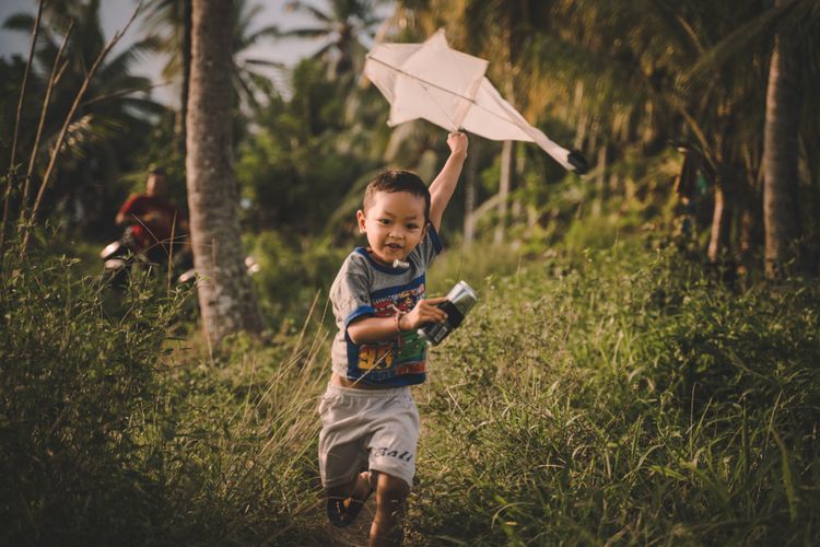 Ilustrasi anak kecil bermain layangan di Bali. 