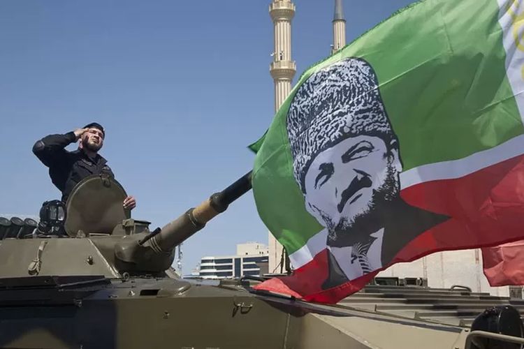 Seorang perwira pasukan khusus Chechnya di atas kendaraan tempur infanteri dengan bendera yang menggambarkan pemimpin Chechnya Ramzan Kadyrov.

