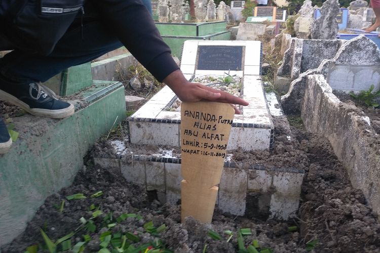 Seseorang memegang nisan kayu bertuliskan nama Ananda Putra alias Abu Alfat di TPU Kemiri, Medan pada Rabu sore (20/11/2019). Ananda tewas dalam penyergapan di Hamparan Perak pada Sabtu (16/11/2019).