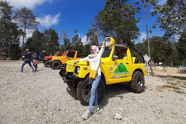 Seorang pengunjung berfoto di depan mobil jeep adventure di Sakura Hills Tawangmangu, Karanganyar, Jawa Tengah.