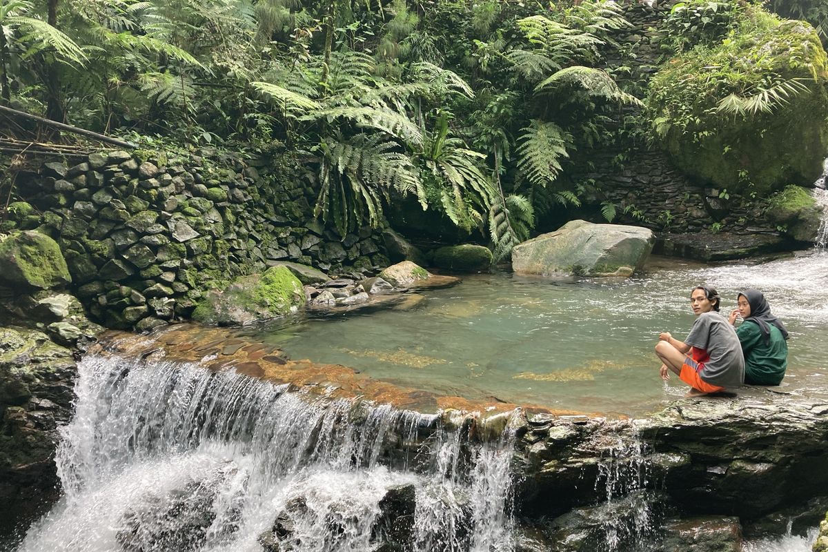 Dua orang wisatawan yang tengah menikmati pemandangan di Curug Balong Endah, Kecamatan Pamijahan, Kabupaten Bogor, Selasa (25/5/2021).