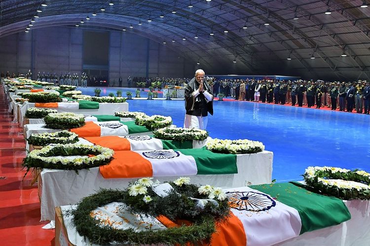 Foto yang diambil pada 15 Februari 2019 memperlihatkan PM India Narendra Modi memberikan penghormatan terakhir di depan peti jenazah 40 tentara yang tewas akibat serangan bom bunuh diri di Kashmir, sehari sebelumnya. 