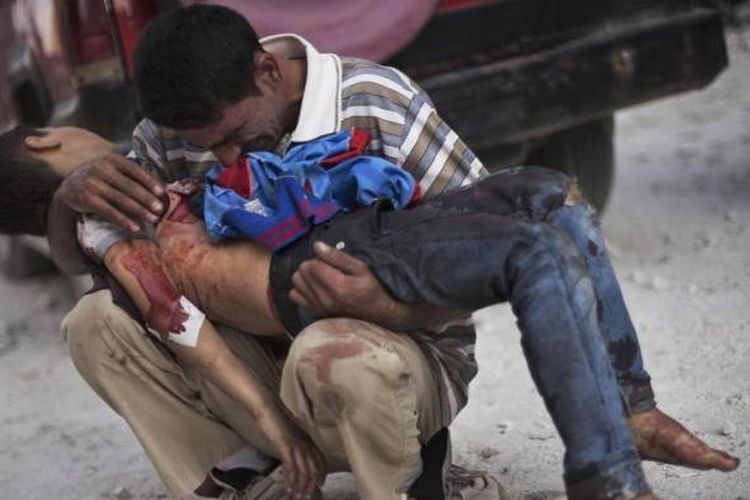 FILE - Pria Suriah menangis sambil memegang jenazah anaknya di dekat RS Dar El Shifa di Aleppo, Suriah, 3 Oktober 2012. Anak itu dibunuh oleh tentara Suriah. Foto ini salah satu dari 20 foto karya fotografer AP yang memenangkan Pulitzer Prize 2013 kategori foto Breaking News.