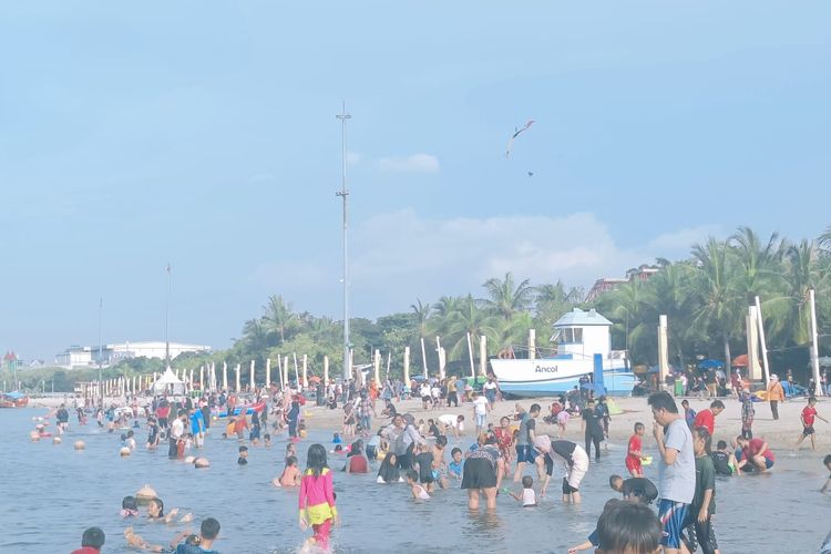 Suasana di Pantai Ancol di hari pertama tahun baru 2023. Ribuan pengunjung memadati pantai dan asyik bermain riang gembira, Minggu (1/1/2023).