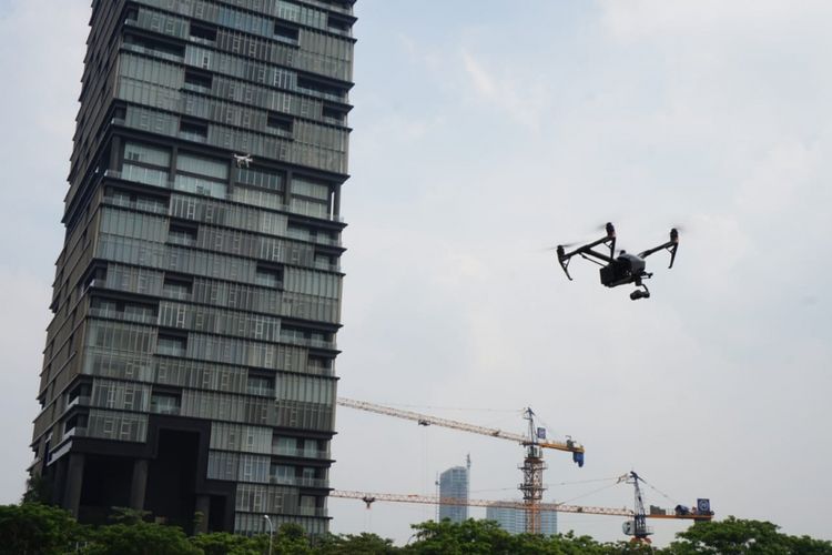 Sebuah drone terbang dengan background gedung pencakar langit.