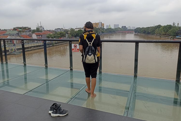 Salah satu pengunjung jembatan kaca Tangerang atau Jembatan Kaca Berendeng di Kota Tangerang, Banten, pada Minggu (21/4/2024). Pengunjung harus melepas alas kaki sebelum melangkah ke lantai kaca di jembatan.