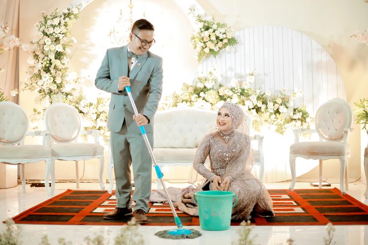 Pengantin pria, Yuniar Ferdiansyah yang masih di pelaminan juga membantu membersihkan air dengan alat pel. Momen itu pun ditangkap oleh Sugeng untuk menjadi konsep foto wedding.