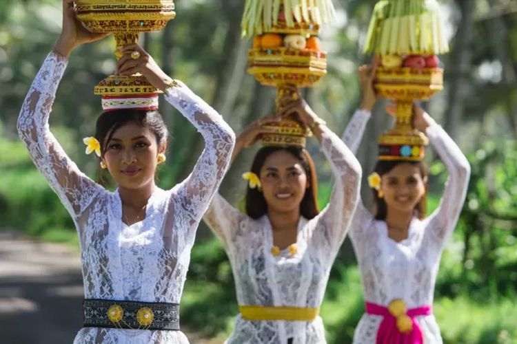 Perempuan Bali menggunakan kebaya dengan selempang warna-warni yang kontras.