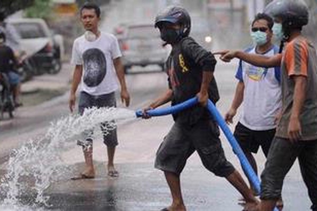 Warga gotong royong membersihkan jalan yang tertutup abu vulkanik di Jalan Kaliurang, Besi, Sleman, DI Yogyakarta, Sabtu (30/10/2010). Letusan Gunung Merapi yang terjadi pada dini hari mengakibatkan hujan abu di sejumlah kawasan di DI Yogyakarta. 