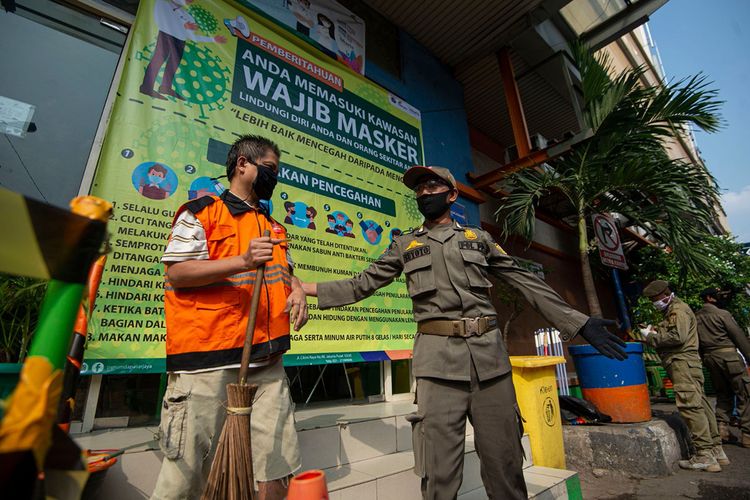 Petugas Satpol PP mengawasi pelanggar aturan pembatasan sosial berskala besar (PSBB) yang melaksanakan sanksi kerja sosial di Pasar Jatinegara, Jakarta, Kamis (11/6/2020). Penindakan itu untuk memberikan efek jera bagi para pelanggar agar mereka patuh terhadap kebijakan PSBB sekaligus meminimalisir potensi penyebaran COVID-19.