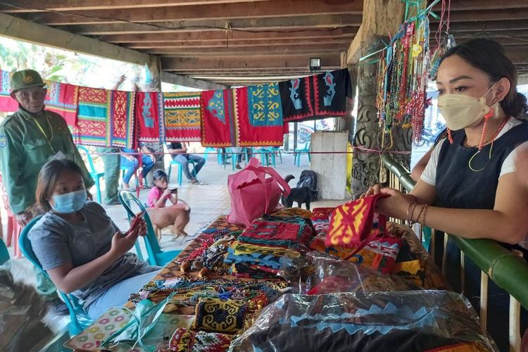 Seorang pengunjung saat membeli kain motif kriookng milik FE Lebiq (76) dan Sisilia Ramla (75) di kolong Lamin Luuq Melapeh, Kampung Linggang Melapeh, Kabupaten Kutai Barat, Kalimantan Timur, akhir Desember lalu.