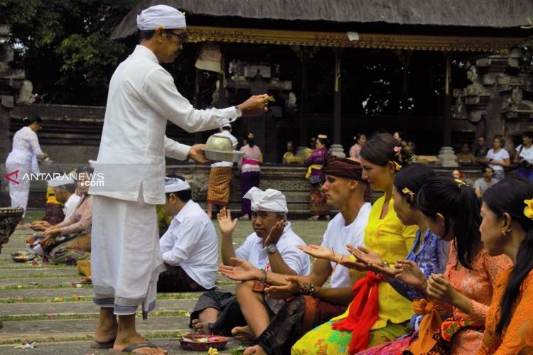 Sepasang turis Polandia, Barteck dan Aneta, ikut persembahyangan dengan masyarakat Hindu Bali, di Pura Dalam, desa pakraman Ubud, Gianyar, Rabu