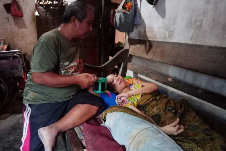 Kondisi Dwi Ayu Prasetya, anak sulung Koestomo, yang lumpuh setelah didiagnosa menderita Amyotrophic Lateral Sclerosis (ALS). Bersama keluarganya, tukang sepatu itu tinggal di Dusun Bandung Krajan, Desa Bandung, Kecamatan Diwek, Kabupaten Jombang, Jawa Timur.