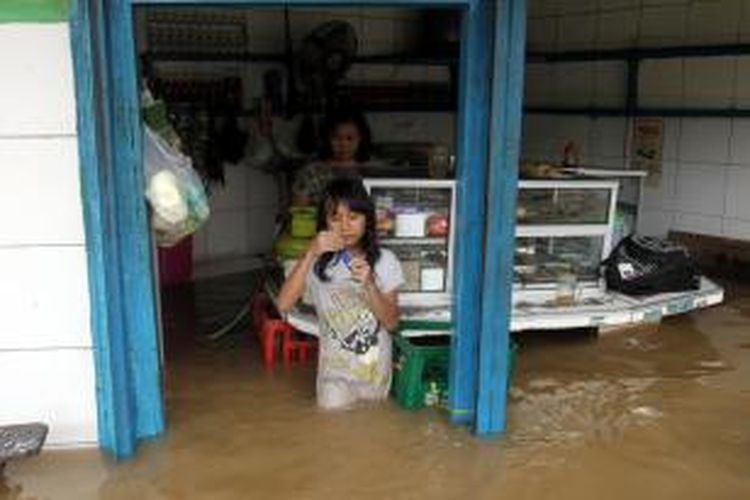 Sebuah warung makan tetap buka melayani pembeli di tengah banjir yang melanda Jalan Jatinegara, Jakarta Timur, Senin (13/1/2014). Sejumlah wilayah di Jakarta terendam banjir akibat curah hujan yang tinggi dan air kiriman dari Bogor. TRIBUNNEWS/HERUDIN
