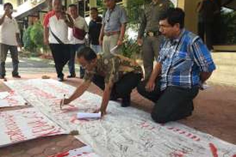 Ketua DPRD Pamekasan, Halili saat membubuhkan tanda tangan dukungan penolakan PP nomor 60 tahun 2016 tentang PNBP di depan kantor DPRD Pamekasan, Jumat (6/1/2017). 