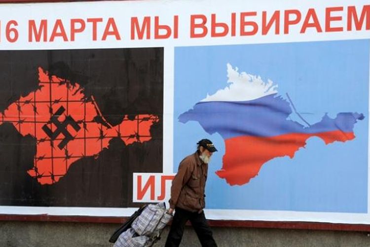 Beberapa warga kota Sevastopol, Crimea berjalan melewati poster besar tentang jadwal referendum 16 Maret mendatang. Referendum itu nantinya akan menentukan apakah Semenanjung Crimea tetap menjadi bagian Ukraina atau bergabung dengan Rusia.