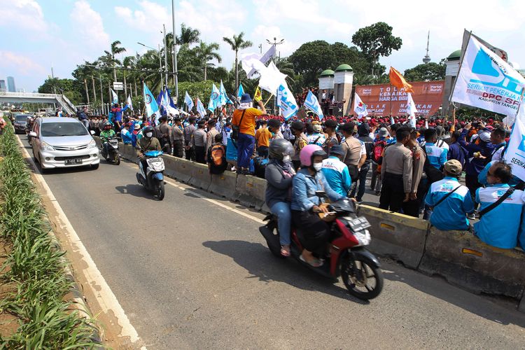 Pengguna jalan melintasi jalur Transjakarta saat terjadi demonstrasi dari elemen buruh  depan Gedung DPR/MPR RI, Jakarta, Selasa (6/9/2022). Mereka menolak kenaikan harga BBM.