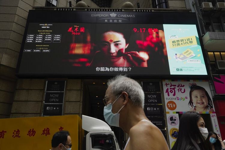 Pada filr September 2020 ini, Orang-orang berjalan melewati layar TV besar yang menampilkan daftar film di sepanjang jalan pusat kota di Hong Kong. 