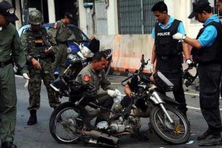 Polisi Thailand memeriksa sebuah sepada motor pembawa bom yang meledak di dekat sebuah pasar di Narathiwat, Thailand Selatan, Jumat (1/3/2013).