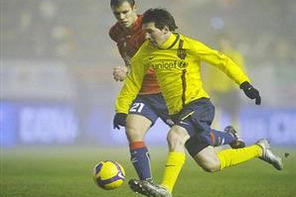 Lionel Messi mencoba melewati lawan dan melepaskan tendangan kaki kiri yang membuahkan gol kemenangan Barcelona atas Osasuna.