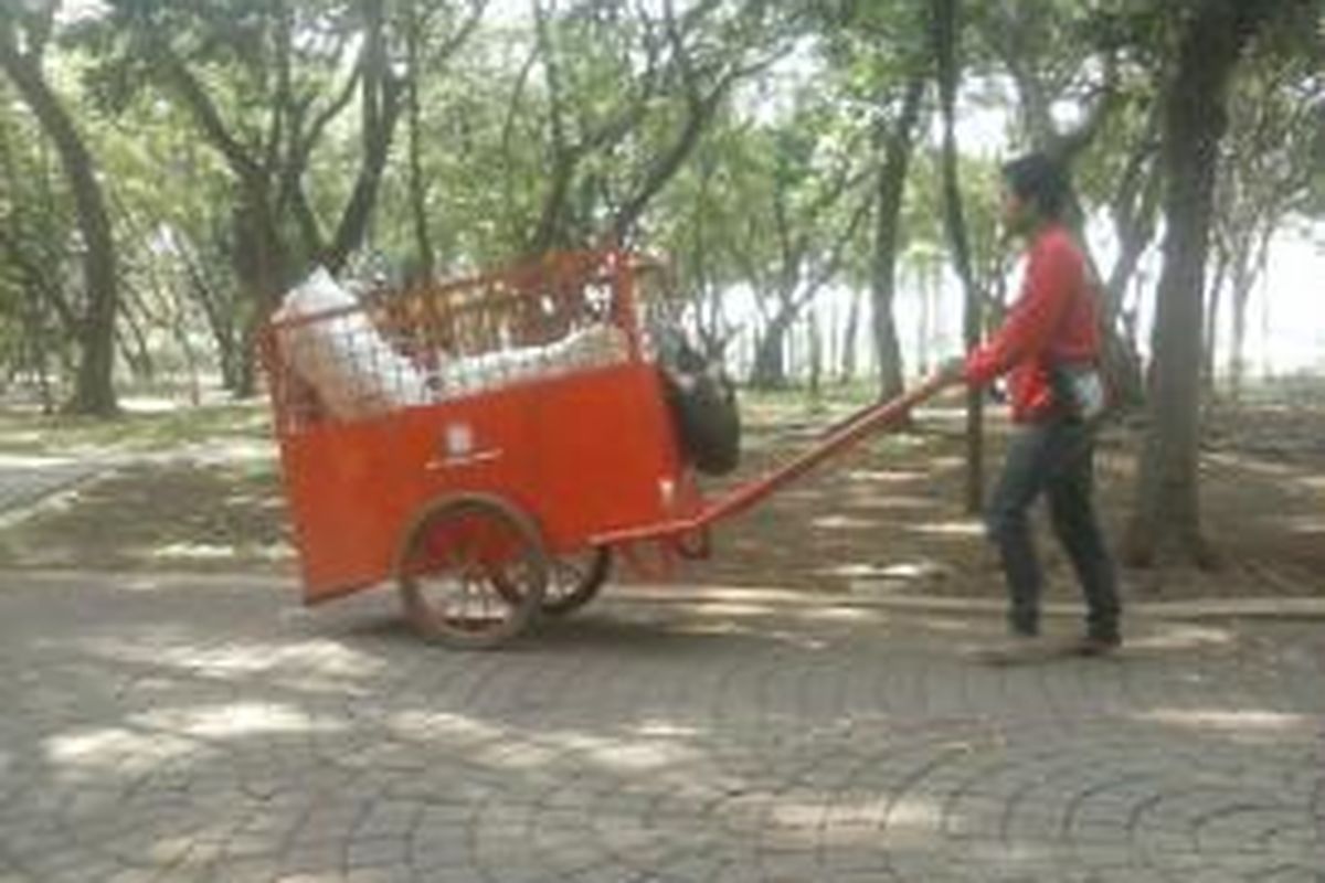 Seorang petugas kebersihan di Monumen Nasional, Gambir, Jakarta Pusat, mengangkut sampah yang kini semakin sedikit sejak razia PKL gencar digelar, Kamis (11/12/2014).