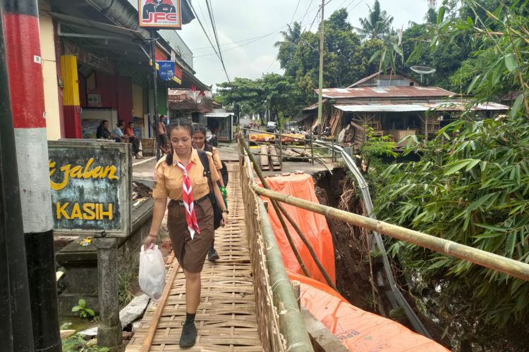 Siswa melintas di jembatan bambu yang dibangun swadaya oleh masyarakat di Lingkungan Bakung, Kelurahan Sukasada, Kecamatan Sukasada, Kabupaten Buleleng, Provinsi Bali, karena ambruk, Jumat (10/2/2023).