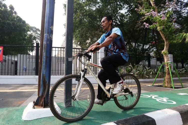 Seorang pesepeda saat melintas di jalur sepeda di Jalan Asia Afrika, Jakarta, Rabu (01/08/2018). Jalur sepeda di sepanjang jalan ini terhalang beberapa tiang lampu penerangan jalan umum (PJU), tiang lampu lalu lintas, hingga tiang rambu penunjuk jalan.