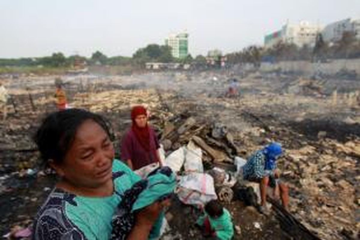 Warga menangis melihat puing bangunan rumahnya yang terbakar di Kampung Pulo Kandang, Jalan Inspeksi Kali Sunter, Kelurahan Kelapa Gading Barat, Kecamatan Kelapa Gading, Jakarta Utara, Selasa (1/10/2013). Kebakaran yang terjadi sekitar pukul 02.30 dini hari tersebut mengakibatkan sedikitnya 700 rumah terbakar.