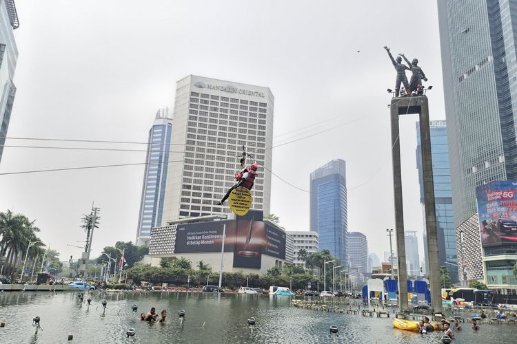 Momen aktivis Greenpeace Indonesia yang membentangkan spanduk protes terkait bencana dan krisis iklim turun dari atas Monumen Selamat Datang Bundaran HI, Jakarta Pusat, Selasa (20/10/2026)