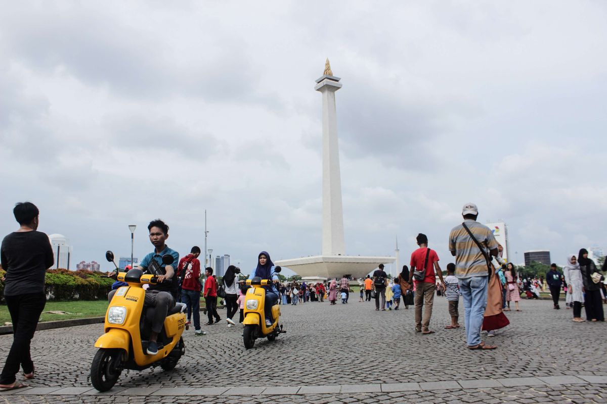 Pengunjung bermain sepeda listrik yang disediakan oleh pengelola di kawasan Monumen Nasional, Gambir, Jakarta Pusat, Minggu (29/12/2019). Jelang penghujung 2019, tempat wisata Monumen Nasional (Monas) ramai dikunjungi wisatawan lokal maupun mancanegara.