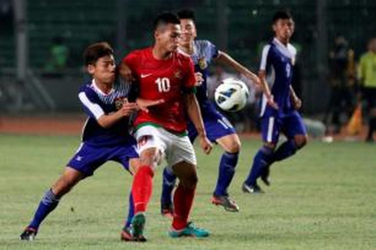 Pemain Indonesia Muchlis Hadi Ning Syaifulloh berjibaku dengan pemain Laos saat berusaha mencetak gol dalam pertandingan Piala AFC U-19 di Stadion Utama Gelora Bung Karno, Jakarta, Selasa (8/10/2013). Indonesia menang 4-0 atas Laos.