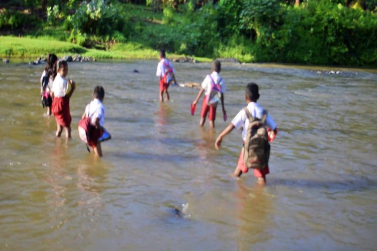 Foto : Anak-anak SD Inpres Blawuk, Desa Nebe, Kecamatan Talibura, Kabupaten Sikka,NTT sedang menyeberangi kali Nangagete untuk pergi ke sekolah, Jumat (5/11/2021).