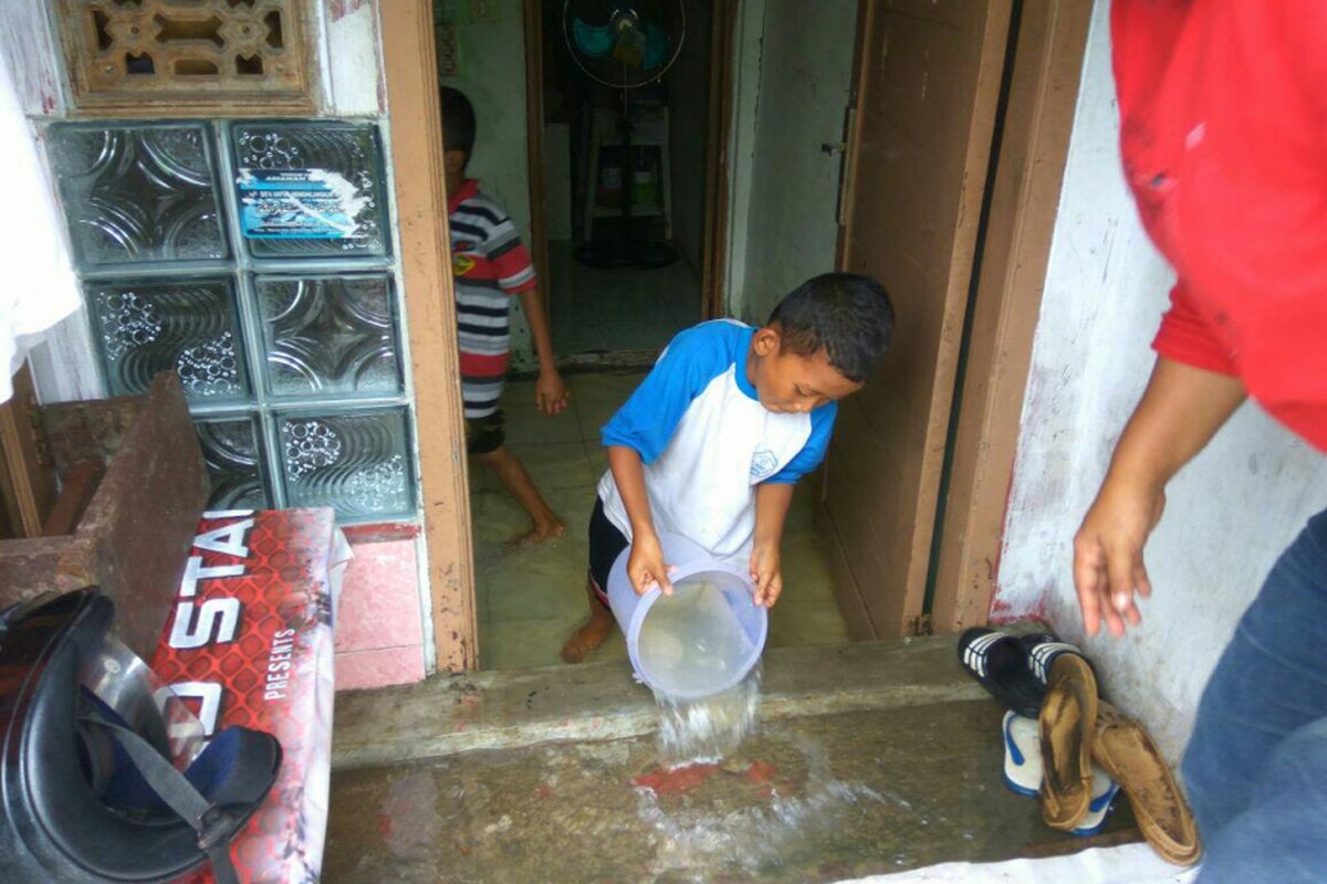 Iin dibantu oleh anak-anaknya membersihkan air yang masuk ke ruang tamu rumahnya di dekat Tanggul Baswedan Kamis (8/2/2018).