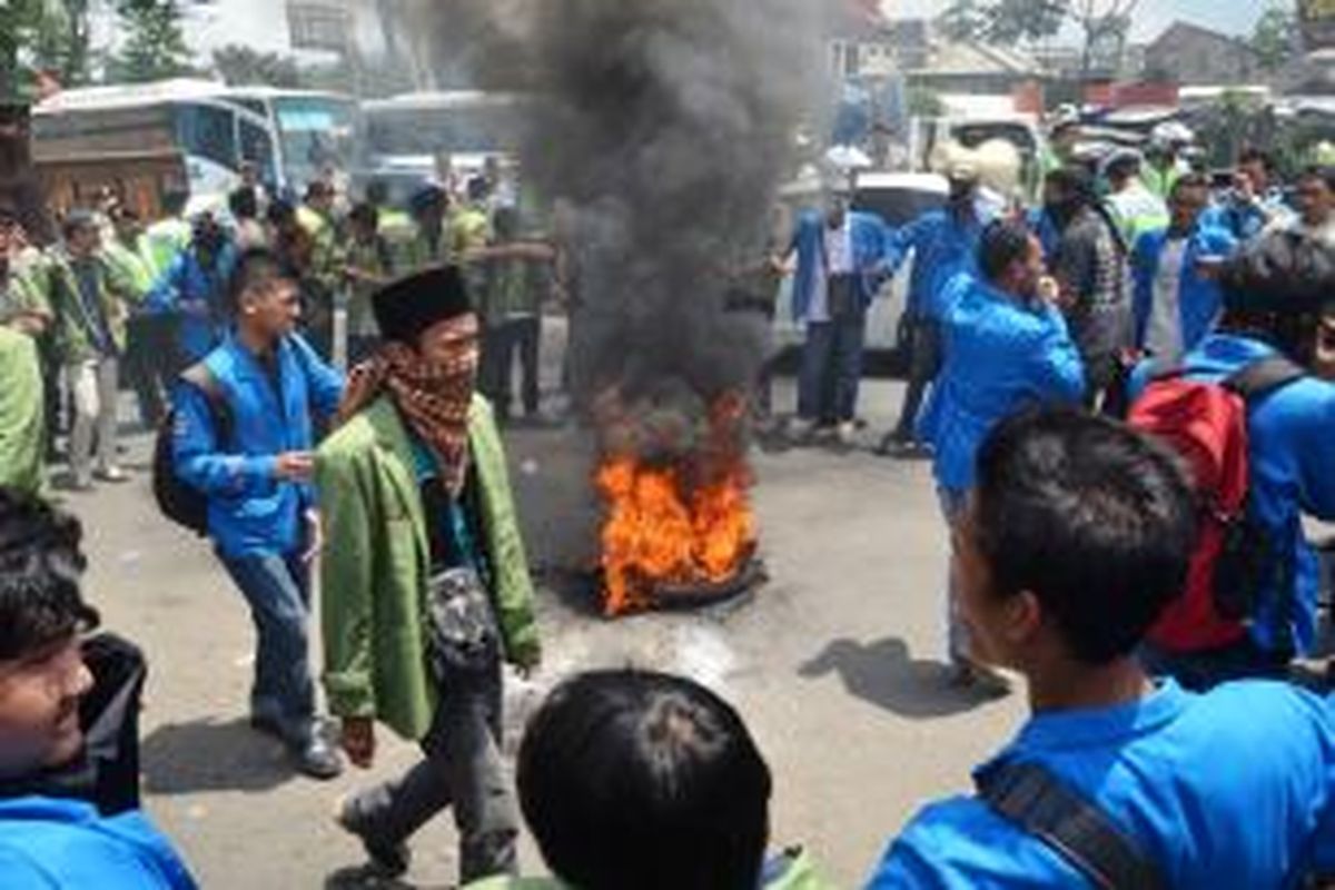Puluhan mahasiswa Universitas Djuanda Bogor, menggelar aksi unjuk rasa, di depan akses pintu Tol Jagorawi, Ciawi, Senin (17/11/2014). Demonstran juga membakar ban bekas sebagai bentuk penolakkan kenaikan harga BBM bersubsidi. K97-14