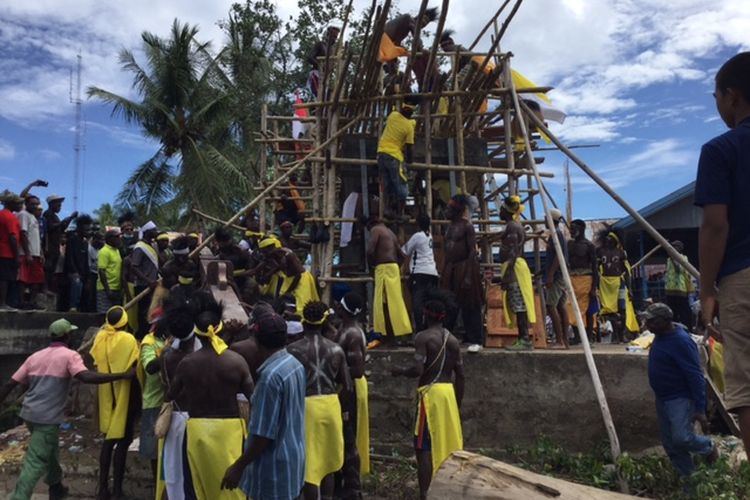 Masyarakat adat Mimika Wee, saat mengangkat salib untuk ditancapkan di tempatnya yang berada tak jauh dari perayaan rekonsialiasi di depan Dermaga Pelabuhan Kokonao, Distrik Mimika Barat, Kabupaten Mimika, Papua, Minggu (24/04/2022).