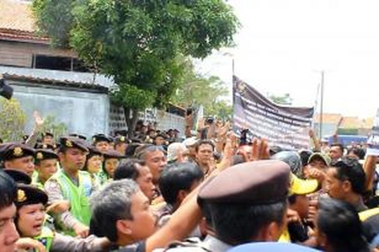 Puluhan warga berunjuk rasa di depan pabrik pembuatan peti mati di Desa Ciperna, Kecamatan Talun, Kabupaten Cirebon, Jawa Barat, Jumat siang (17/10/2014). Pendemo menuntut pengusaha menaikan upah buruh yang rendah, dan segera mendaftarkan buruh ke BPJS.