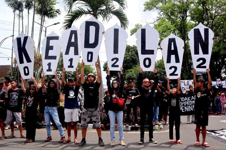 Suporter Arema, Aremania dan masyarakat membentangkan ornamen tulisan KEADILAN saat melakukan aksi damai terkait Tragedi Kanjuruhan untuk menuntut keadilan yang dilaksanakan serentak di sejumlah titik Kota Malang, Minggu (27/11/2022) siang.