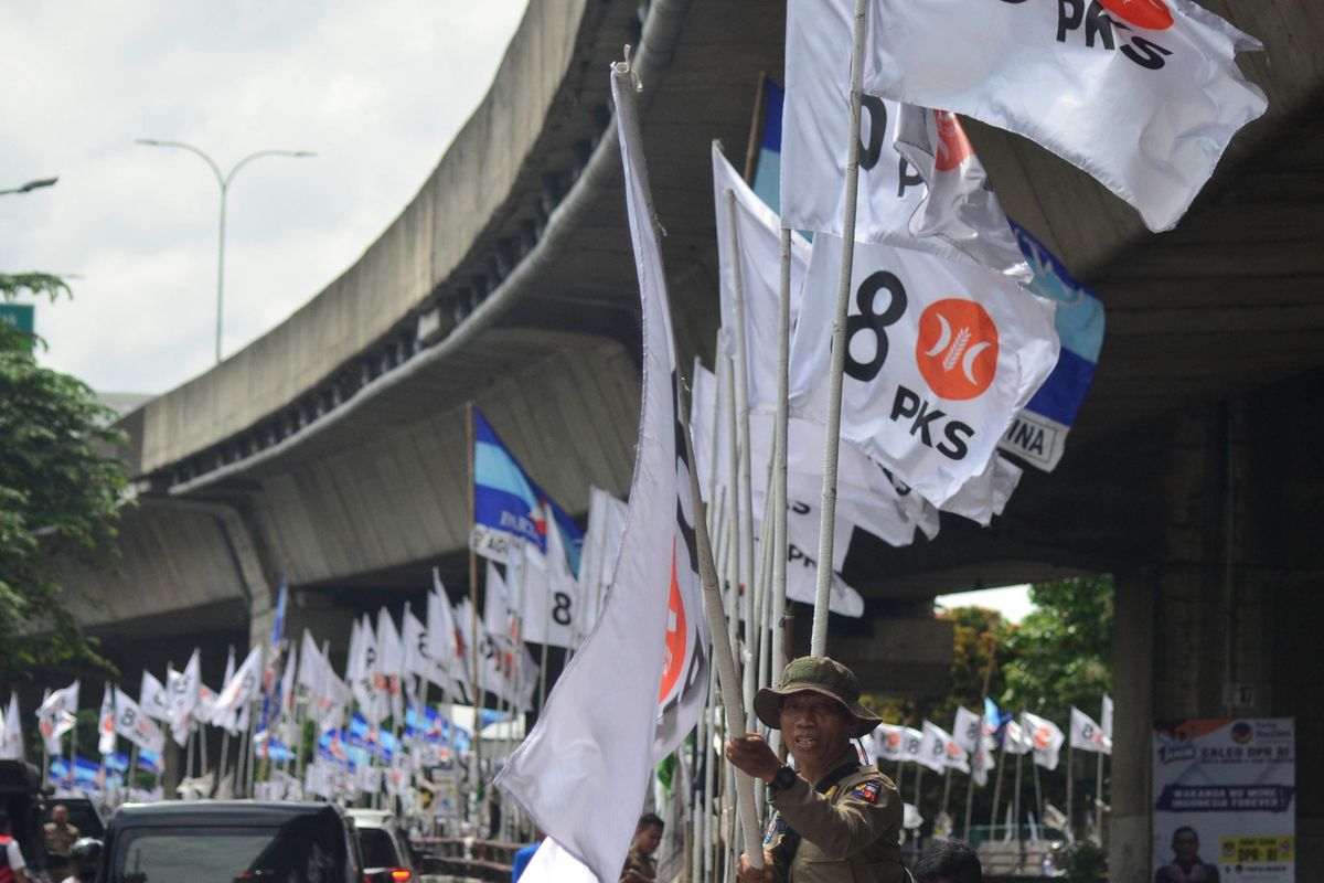 Seorang petugas Satpol PP Kota Bogor sedang menertibkan alat peraga kampanye (APK) yang terpasang di Jalan Raya Sholeh Iskandar, Kota Bogor, Jawa Barat, Selasa (23/1/2024).