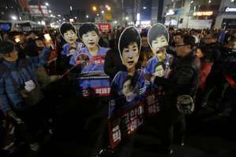 Pengunjuk rasa membawa poster bergambar Presiden Park Geun-hye, Sabtu (31/12/2016) malam mendesak penggulingan presiden yang saat ini tengah diproses Mahkamah Konstitusi.
