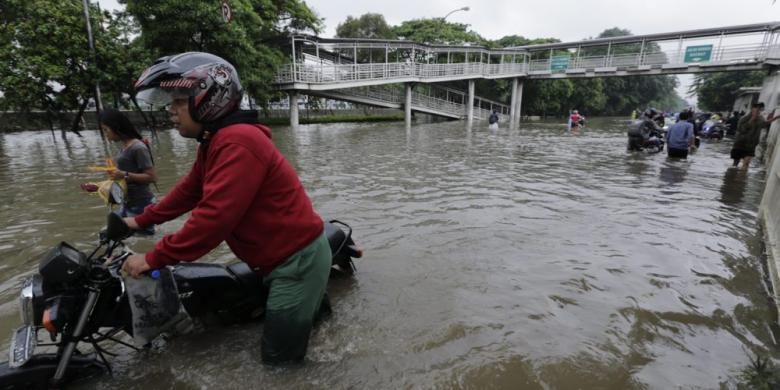 Warga menggunakan sepeda motor berupaya menerobos banjir di Jalan Perintis Kemerdekaan, Pedongkelan, Jakarta, Senin (9/2/2015). Curah hujan yang tinggi mengakibatkan sejumlah tempat di ibu kota terendam banjir.