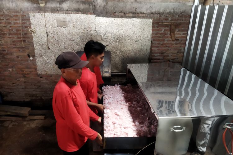 Para pekerja memasukkan cacahan botol Yakult bekas ke dalam mesin oven di CV Bina Usaha Mandiri di Nogosari, Boyolali, Kamis (7/3/2024).