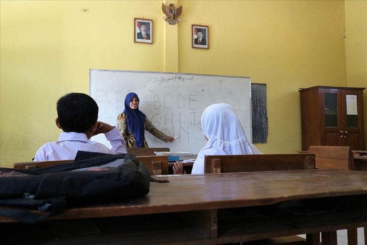 Salah satu guru SDN Sumberaji II, Sriami, membimbing 2 murid barunya, Selaa (16/11/2019). Sekolah dasar itu berada di Dusun Ngapus, Desa Sumberaji, Kecamatan Kabuh, Kabupaten Jombang, Jawa Timur.