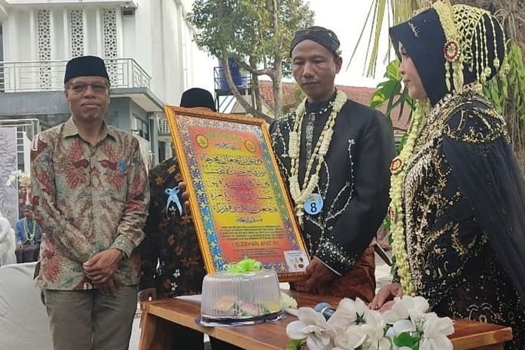 Pasangan pengantin menunjukkan mahar berupa lukisan kaligrafi dan getuk gondok saat Nikah Bareng Meriah di Unimma, Magelang, Selasa (2/7/2024).