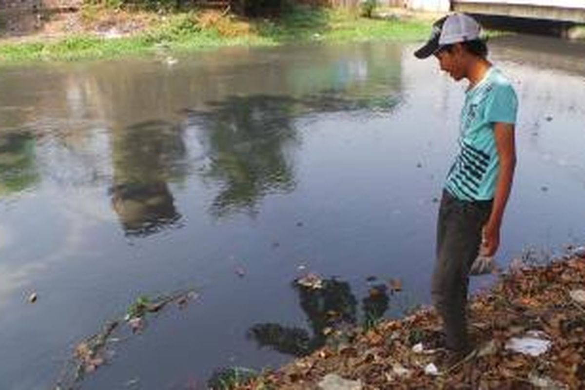 Salah satu warga mengamati pinggiran Kalimalang untuk mengkap ikan yang mabok akibat dugaan pencemaran yang terjadi. Selasa (30/9/2014).
