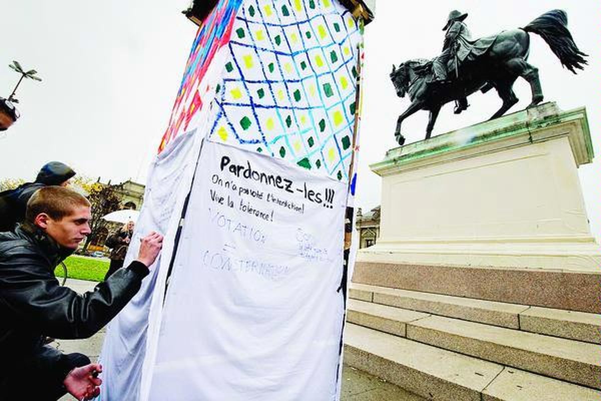 Seorang lelaki menulis slogan pada minaret simbolis di Place Neuve, Geneva, Swiss, Senin (30/11), sebagai ungkapan protes atas hasil referendum sehari sebelumnya yang melarang pembangunan menara masjid baru di Swiss. Slogan itu bertuliskan 