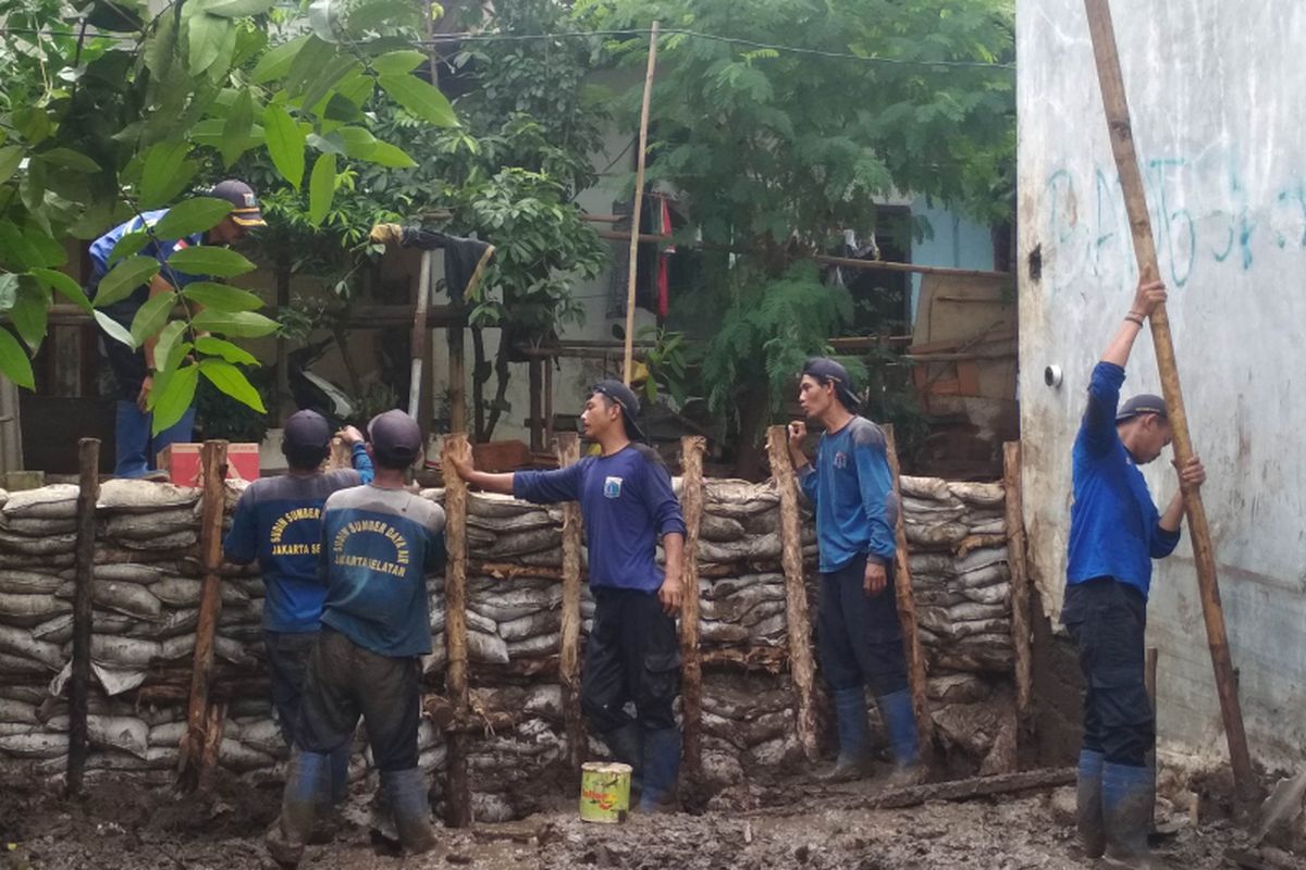 Enam orang petugas dari Dinas SDA tenga membangun pondasi dari Tanggul Permanen di Kelurahan Jatipadang, Jakarta Selatan pada Selasa (15/1/2019).