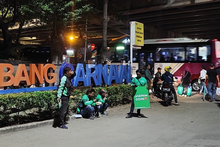 Sejumlah pengemudi ojek online (ojol) tampak tengah ngetem di depan Gerbang Karnaval, Ancol, Jakarta Utara, Minggu (4/6/2023) malam.