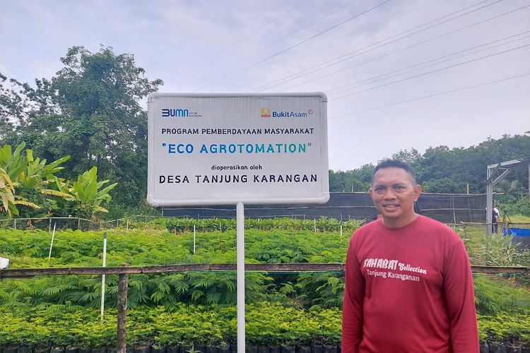 Zailani berdiri di depan bibit-bibit pohon yang digunakan untuk reklamasi di lahan tambang PTBA