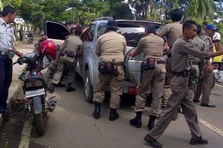 Belasan aparat Satuan Polisi Pamong Praja (Satol PP) di Kabupaten Bone Sulawesi Selatan tengah menggotong sebuah mobil dinas milik mantan pejabat setempat yang enggan dikembalikan meski telah pensiun. Rabu, (22/05/2013).
